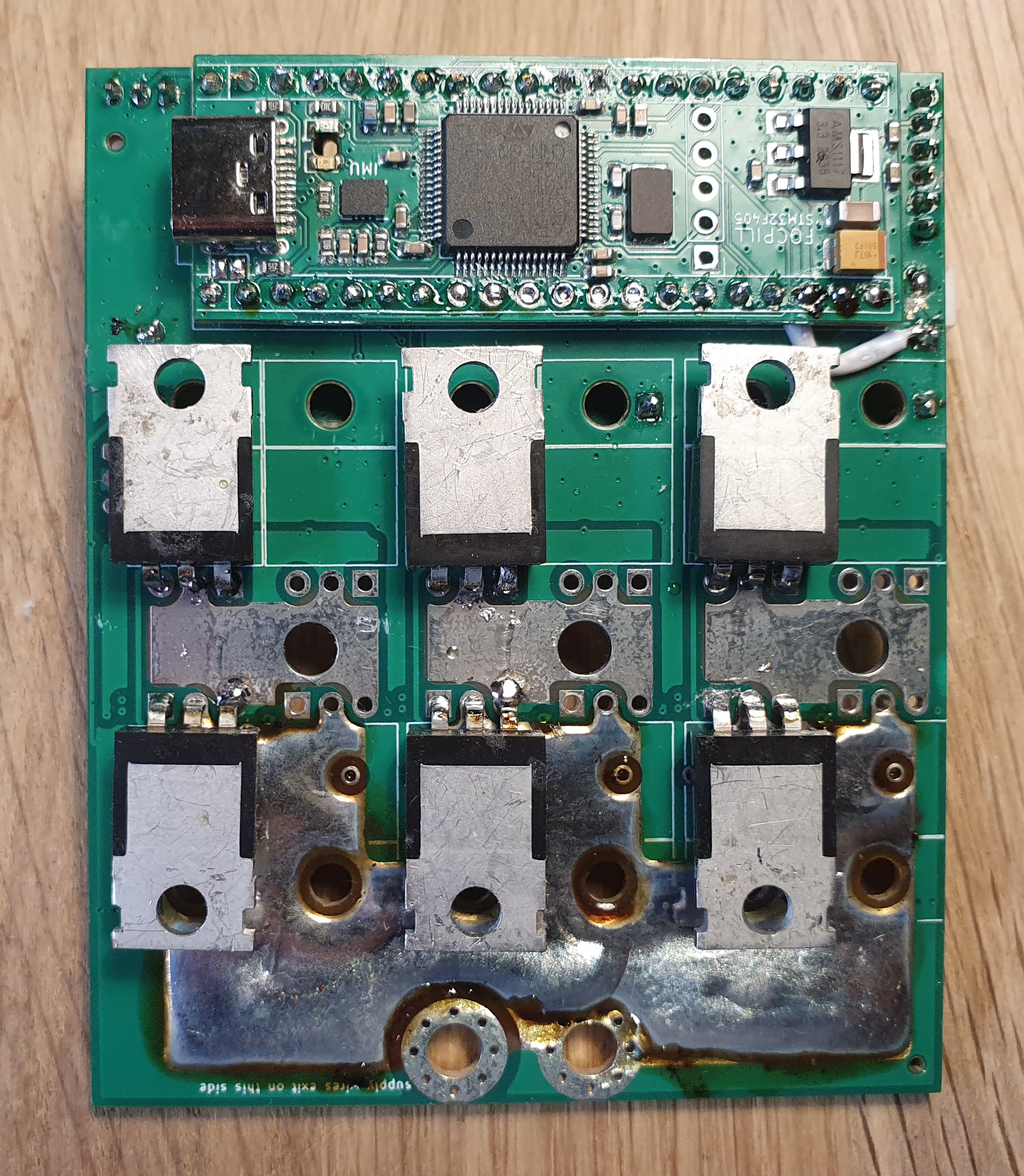 The controller's power stage board: nine TO-247 MOSFETs arranged as three half-bridges over heavy soldered copper bus, with the STM32 module mounted along the top edge