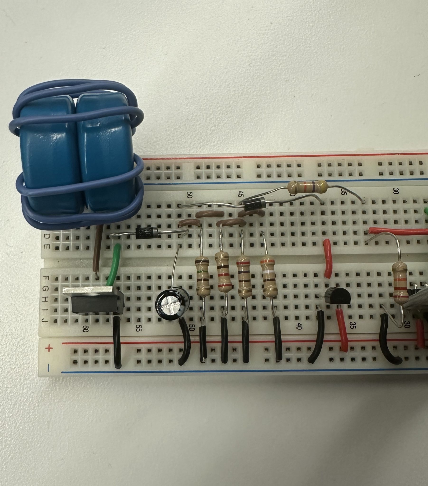 The converter half of the breadboard, with a hand-wound inductor on a blue double core, the MOSFET, electrolytic capacitor, diodes, and the parallel load resistors